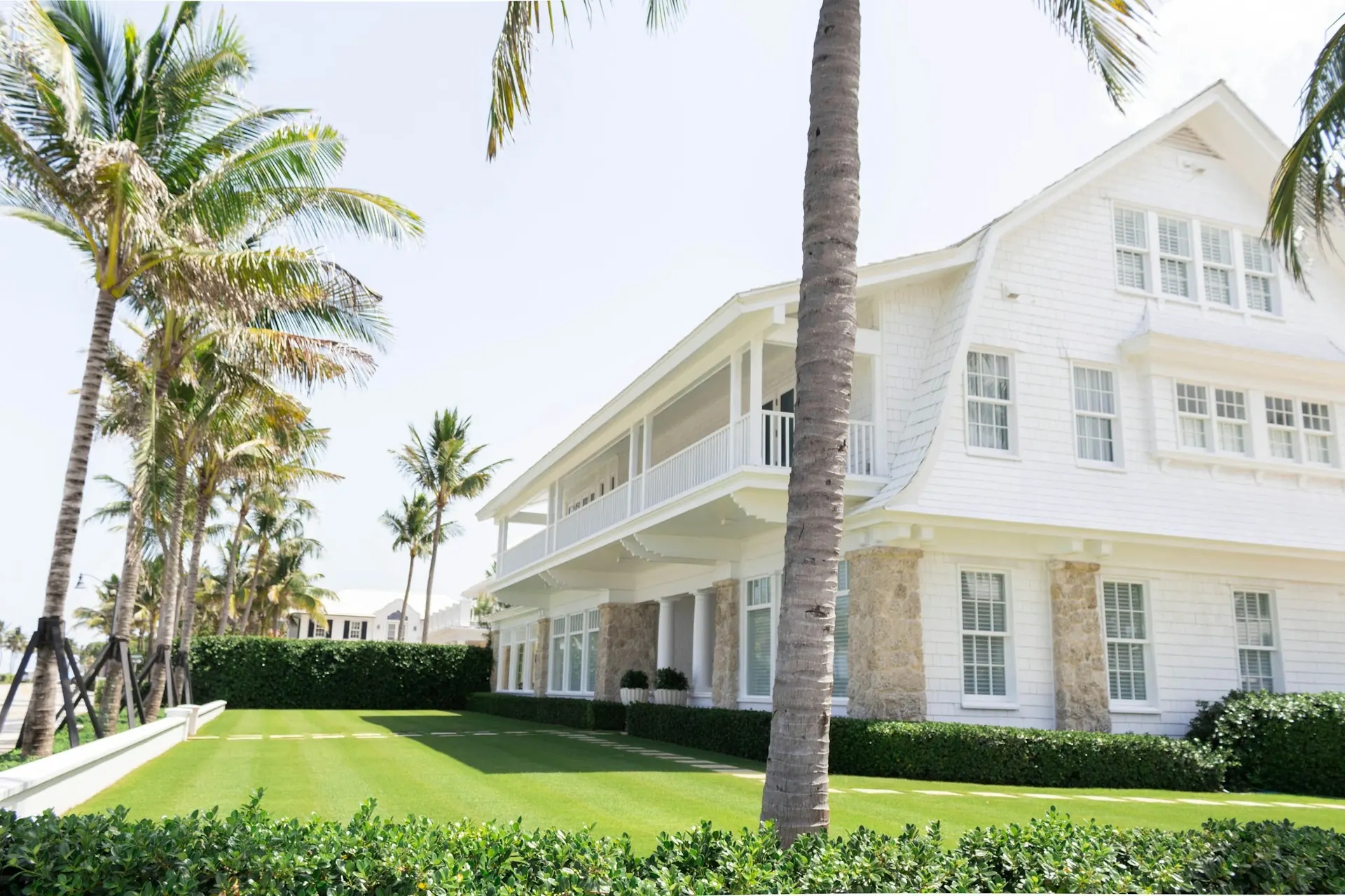 White custom home with palm trees and a manicured lawn